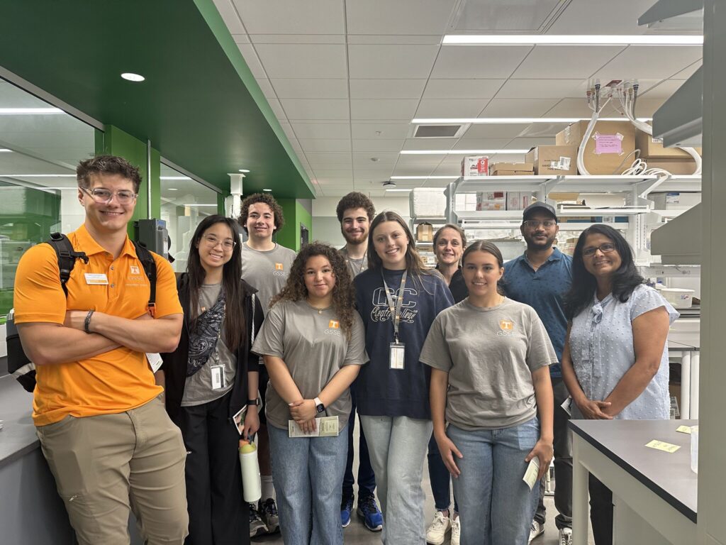 This photo features Dr. Jagadamma and the lab team with the high school students.
