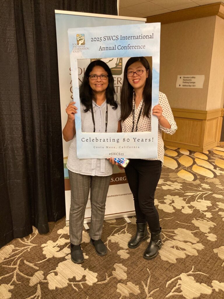 The photo features Dr. Jagadamma (left) with Dr. Sutie Xu (right), at the 2025 SWCS International Annual Conference