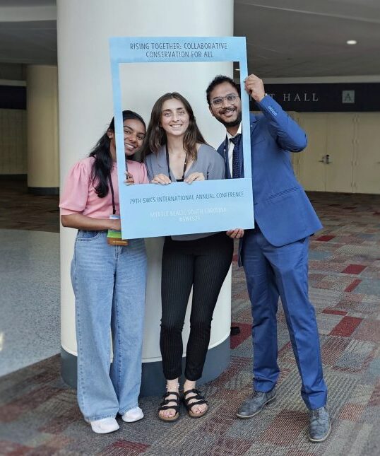Students with picture frame at the 2024 Soil and Water Conservation Society Annual Meeting. 