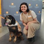 Master's student Ashleigh Montgomery sitting beside UT Mascot Smokey.