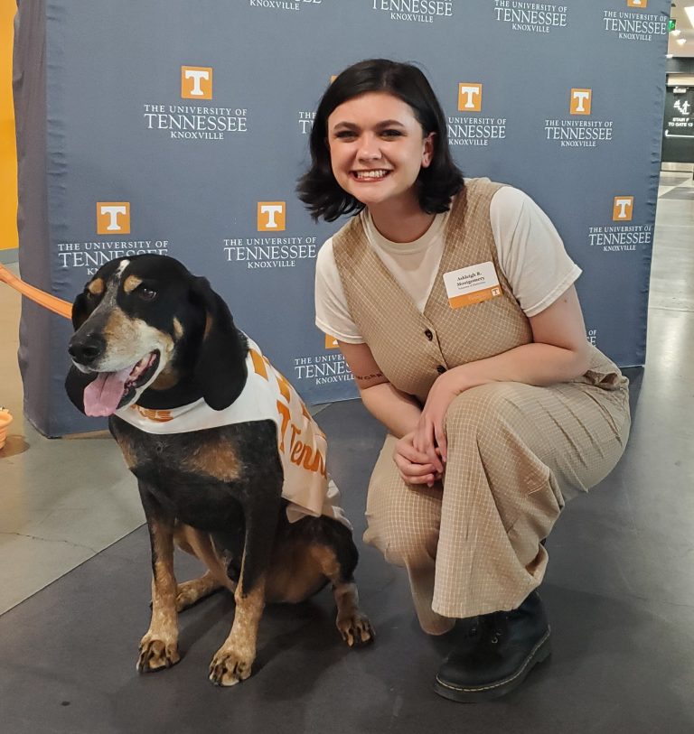 Master's student Ashleigh Montgomery sitting beside UT Mascot Smokey.