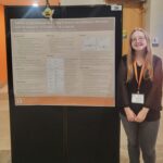 Emily Walker standing beside her poster presentation at the 2022 UTK Discovery Day event.