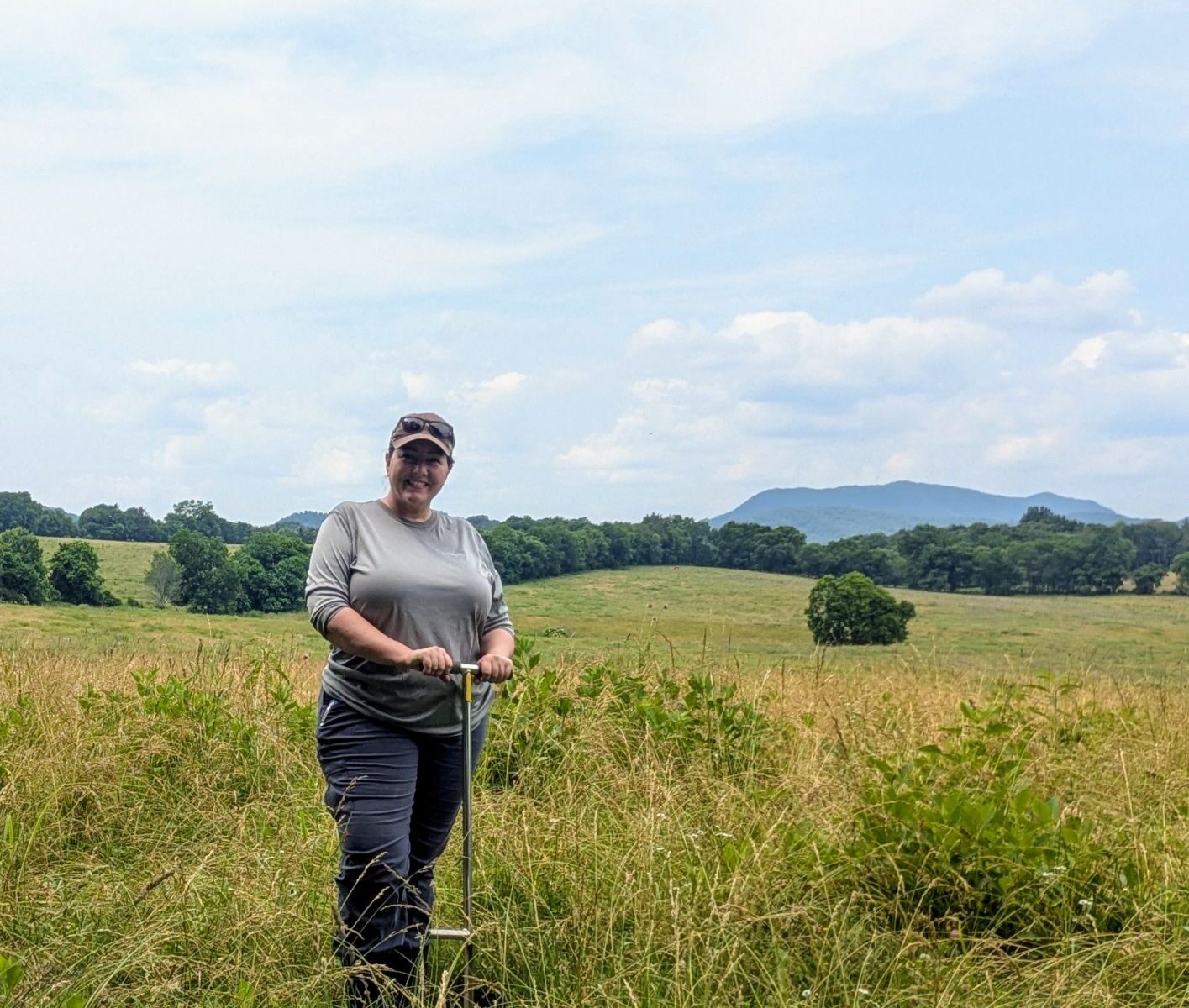 Amber poses with a soil probe while collecting soil samples for her master's. work.