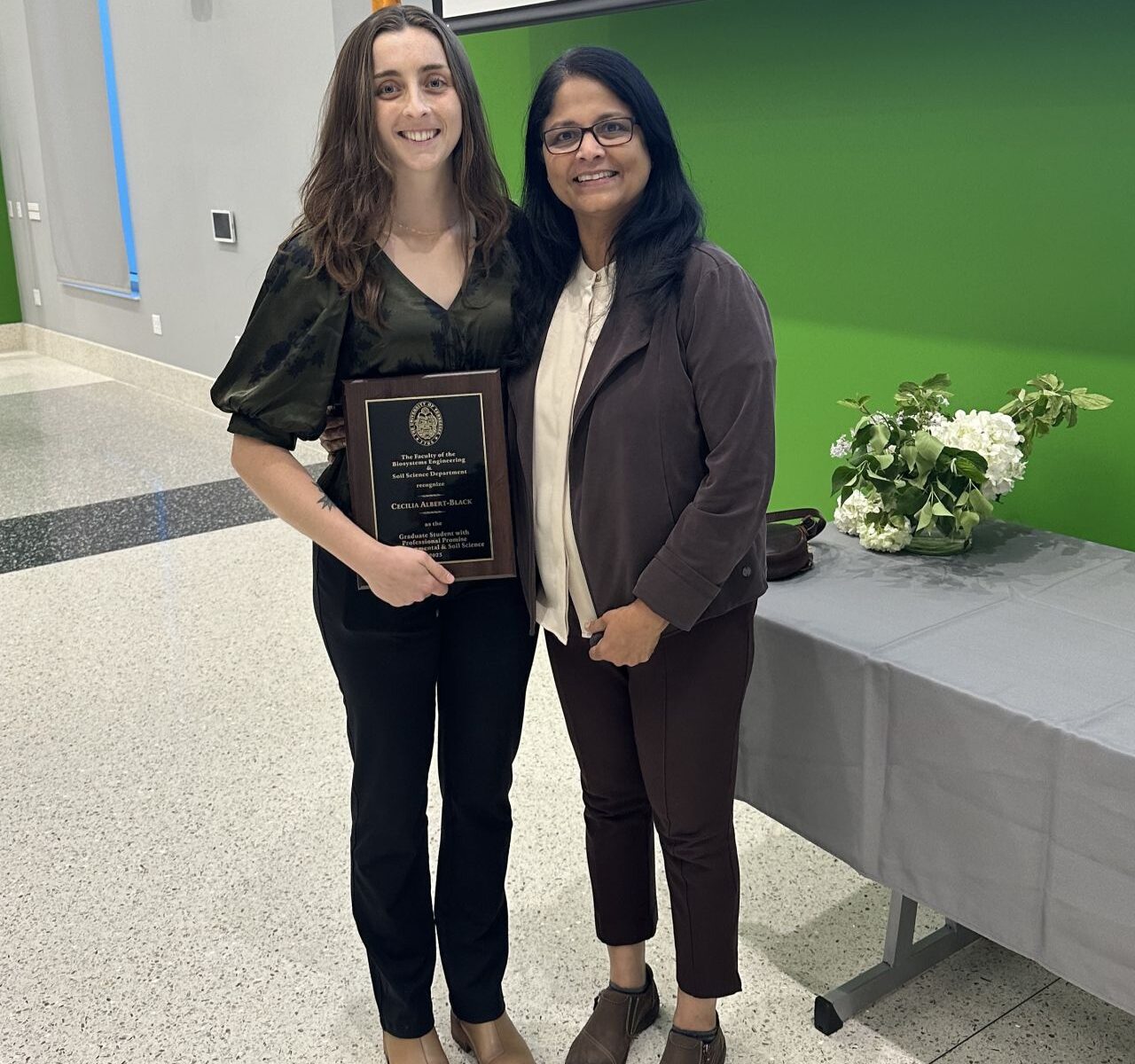 The photo presents Dr. Jagadamma (right) with Cecelia (right), carrying her graduate student with the Professional Promise Award.