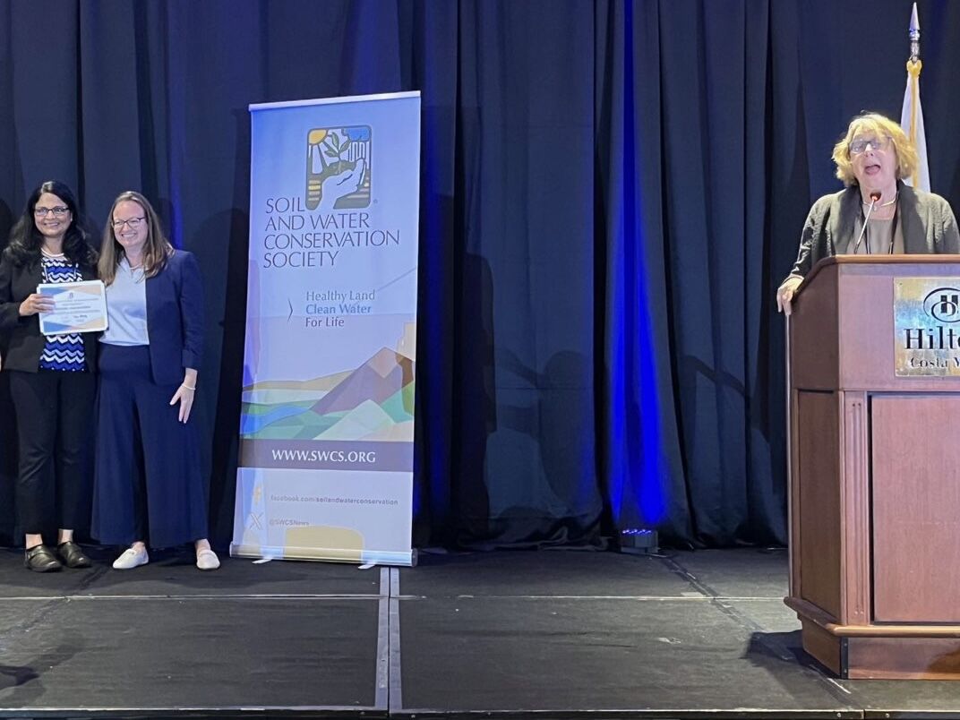 This photo presents Dr. Jagadamma receiving the 2025 Conservation Research Award from SWCS CEO Clare Lindahl