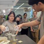 This photo features high school students pouring water to simulate the water infiltration and erosion in tilled and no-till soils.